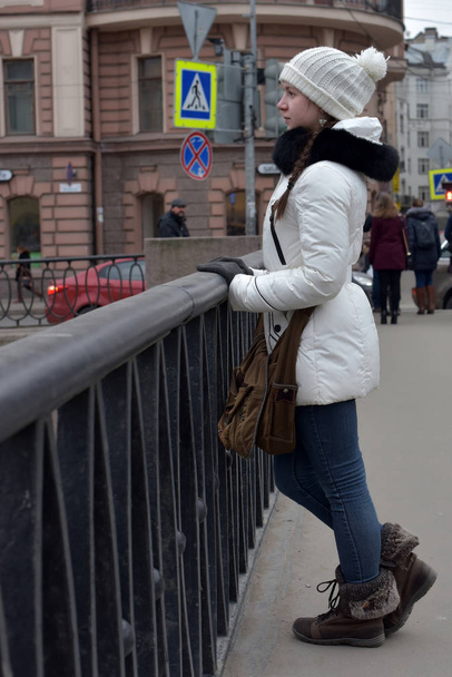 Teen girl in a white coat and hat on the waterfront. - Foto, Bild