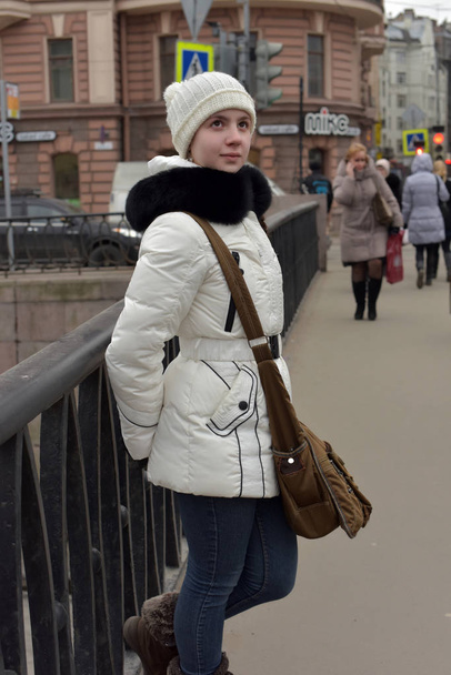 Teen girl in a white coat and hat on the waterfront. - Photo, Image