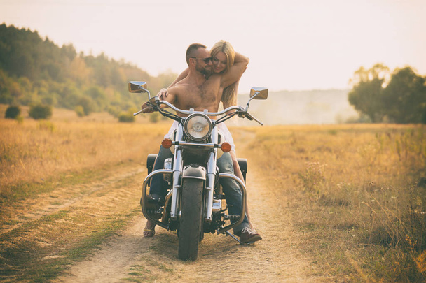 Lovers on a motorcycle in a field - Фото, изображение