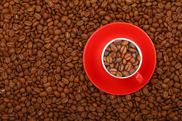 Koffiebonen in rode kop met schotel boven bekijken - Foto, afbeelding