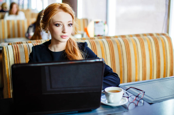 Portrait of a young beautiful businesswomen enjoying coffee during work on portable laptop computer, charming female student using net-book while sitting in cafe bar interior during morning breakfast - Foto, afbeelding