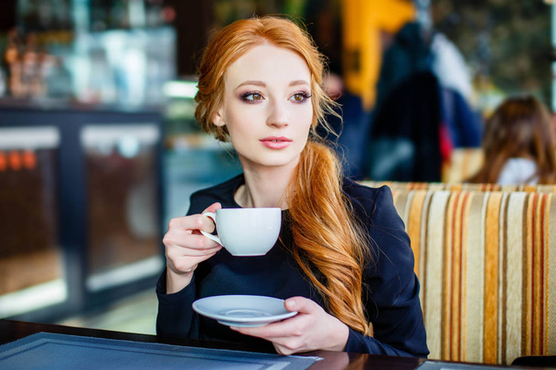 Pretty redhead young woman in the cafe with cup of tea - Fotoğraf, Görsel
