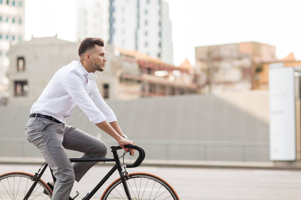 man with headphones riding bicycle on city street - Φωτογραφία, εικόνα