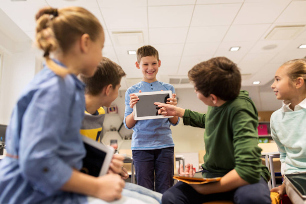 skupina šťastných dětí s tabletovým PC ve škole - Fotografie, Obrázek