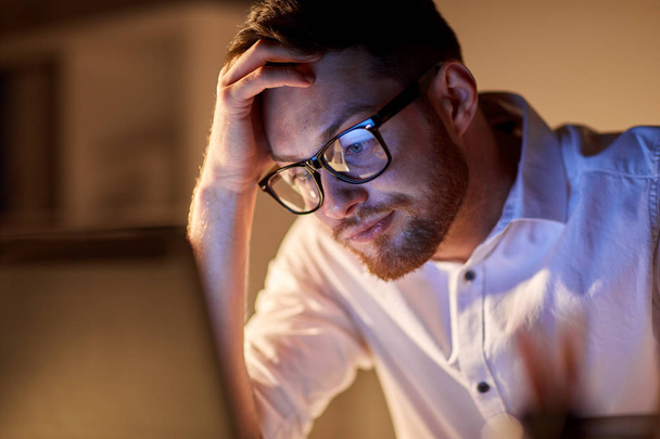 businessman with laptop thinking at night office - Foto, Bild