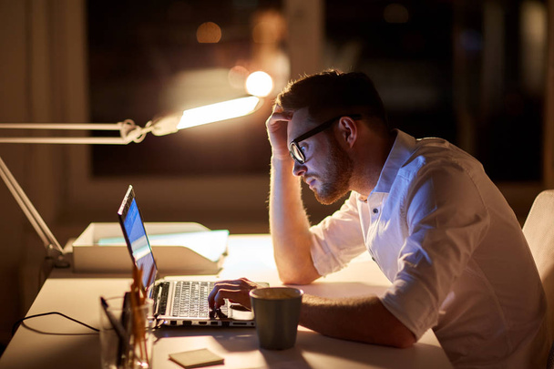 businessman typing on laptop at night office - Zdjęcie, obraz