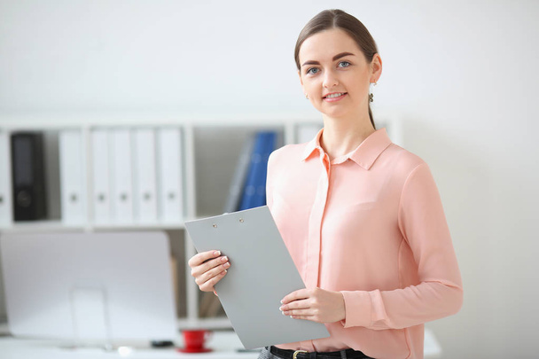 Portrait of business woman looking at the camera holding a folder in her hands and smiling - Fotoğraf, Görsel