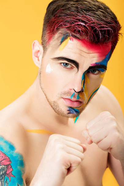 portrait of young man with colored face paint on yellow background. Professional Makeup Fashion. fantasy art makeup - Valokuva, kuva