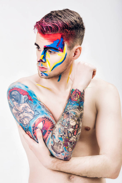 portrait of young attractive man with colored face paint on white background. Professional Makeup Fashion. ffantasy art makeup - Foto, immagini