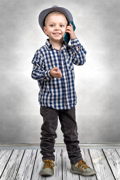 A little boy in a hat talks on his mobile phone.Little boss . - Foto, imagen