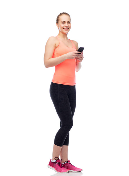 happy smiling sportive young woman with smartphone - Foto, Imagem