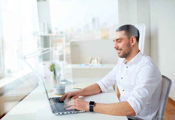 happy businessman typing on laptop at office - Фото, зображення