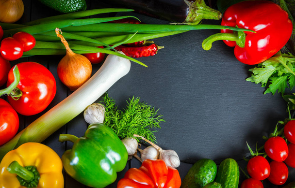 Ekspozycja z bliska świeżych warzyw organicznych, skład z różne surowe warzywa organiczne, papryka i pomidor, ogórek, cebulę i czosnek, na stole Cegła czarny. - Zdjęcie, obraz