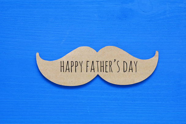 Blauwe houten achtergrond en papier snor. vaders dag concept - Foto, afbeelding