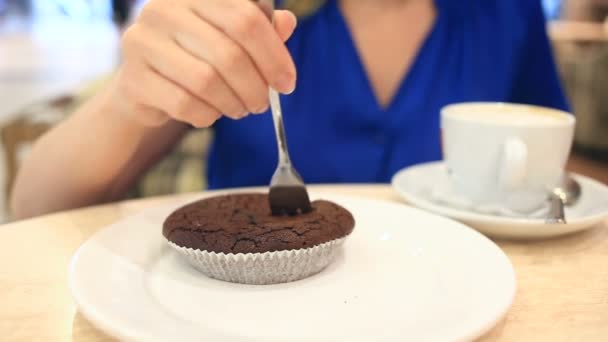 Woman in a cafe drinking coffee with chocolate cake - Filmati, video