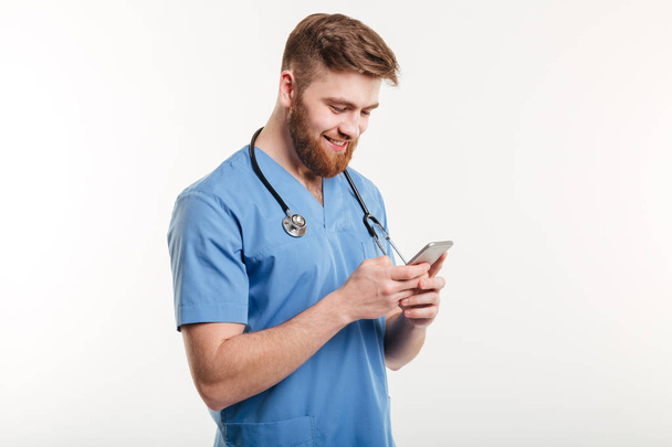 Portrait of man doctor with stethoscope using smartphone. - 写真・画像