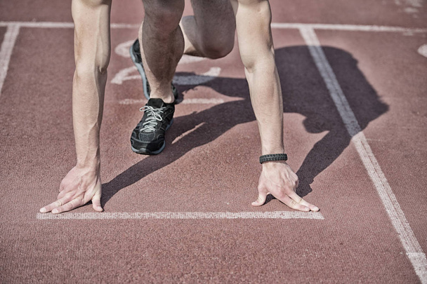 man runner with muscular hands, legs start on running track - Foto, afbeelding