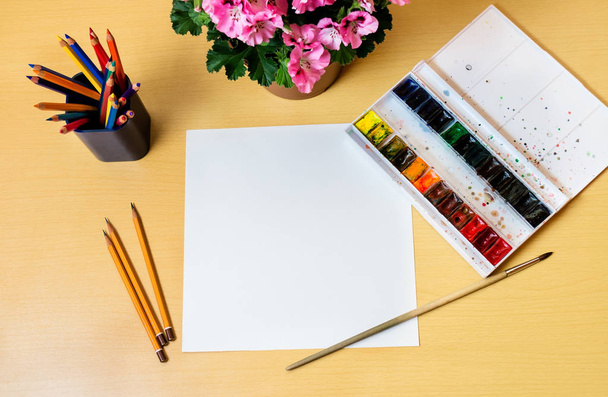 Värikynät, akvarelli ja valkoinen arkki pöydällä
 - Valokuva, kuva