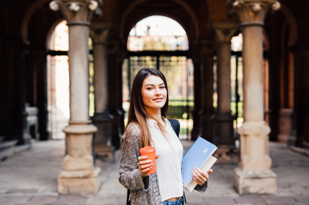 Giovane ragazza studente di bellezza con quaderni all'aperto l'università bere una tazza di caffè
 - Foto, immagini