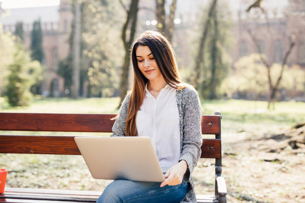 Dziewczyna Student za pomocą laptopa na ławce w parku, w pobliżu kampusu - Zdjęcie, obraz