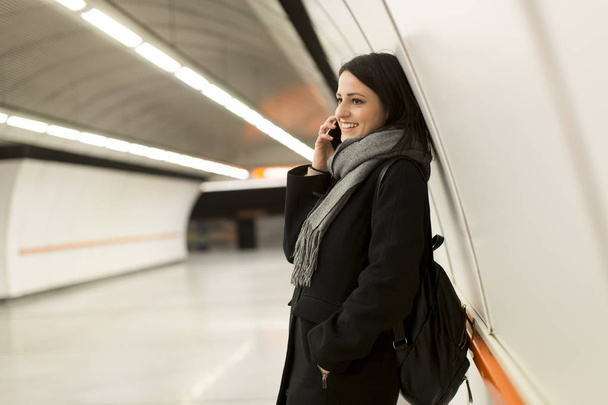 Молода жінка стоїть на станції метро
 - Фото, зображення