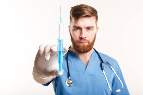 Close up portrait of a serious surgeon holding a syringe - Фото, изображение
