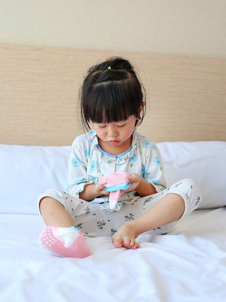 Adorable little girl trying to put a socks on the bed. - Фото, изображение