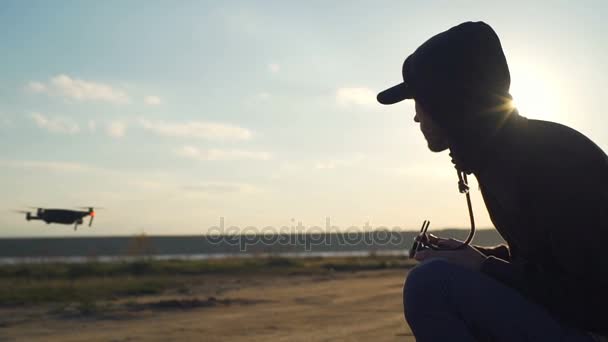 Távirányítóval a fiatal férfi ül, és keresi a repülő drone - Felvétel, videó