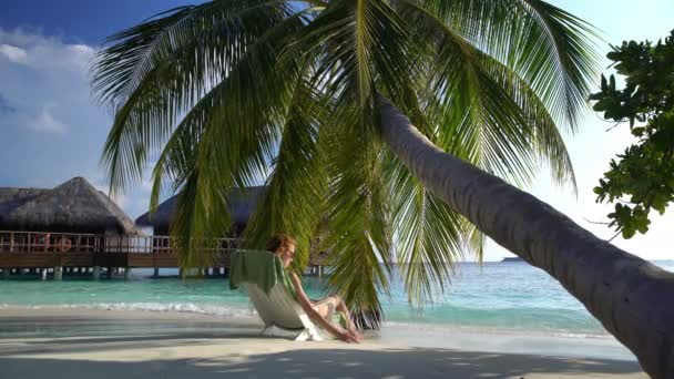 Mladá štíhlá žena užívat dovolenou na lehátku na tropické pláži. - Záběry, video