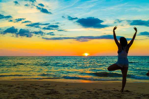 Mujer silueta con postura de yoga en la playa de mar
  - Foto, imagen