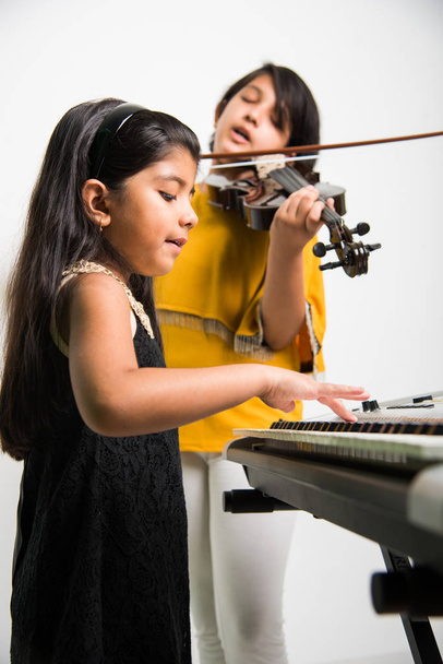 lapset ja musiikkikonsepti - intialaiset pikkutytöt soittamassa soittimia, kuten pianoa, näppäimistöä tai viulua
 - Valokuva, kuva