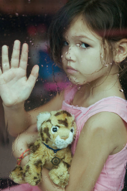 κορίτσι που κάθεται κοντά σε παράθυρο με το παιχνίδι - Φωτογραφία, εικόνα