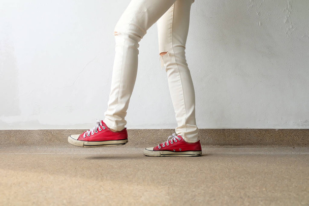 Foto de primer plano de una mujer que usa zapatillas rojas en el fondo de hormigón
 - Foto, imagen