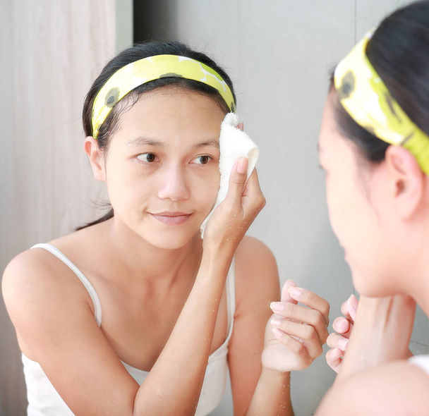 Woman applying foam cream to face reflect with bathroom mirror. - Foto, afbeelding
