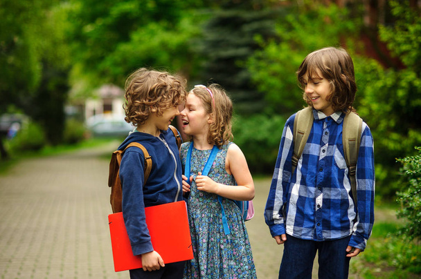 Carino piccoli studenti scolastici chiacchiere vivace sul cortile della scuola
. - Foto, immagini