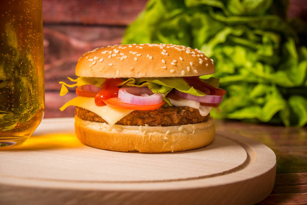 Hamburger és sör fából készült táblán - Fotó, kép