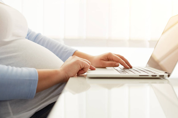 Close up of pregnant woman with laptop - Fotó, kép