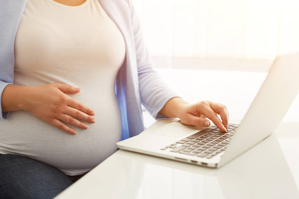 Pregnant woman working on laptop - Foto, afbeelding