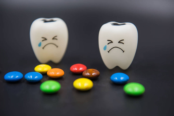 Модель Симпатичные игрушки зубы и красочные конфеты в стоматологии на черном фоне
 - Фото, изображение