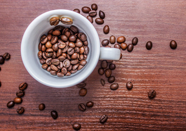 Cup with coffee beans on a brown tree - Photo, Image