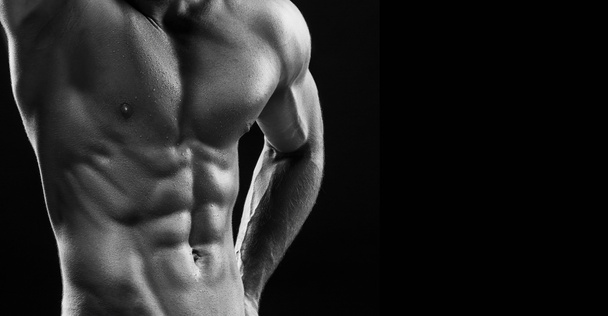The torso of attractive male body builder on black background. - Photo, image