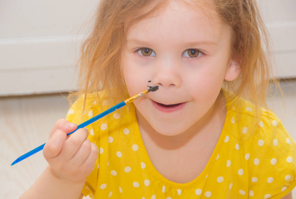 a child draws on a face brush and watercolor. - Foto, Imagen