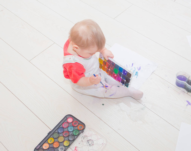 draws the child with a brush and watercolor . - Foto, Imagen