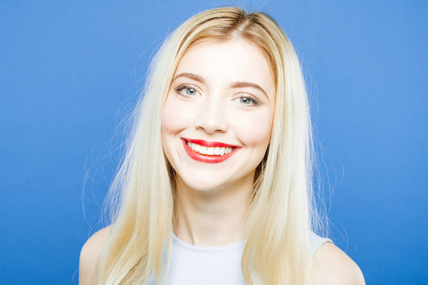 Front View of Amazing Woman with Long Blond Hair and Toothy Smile Posing on Blue Background in Studio. - Foto, Bild