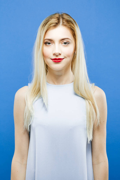 Portrait of Attractive Blonde with Long Hair Wearing Elegant Dress Posing on Blue Background in Studio. - 写真・画像