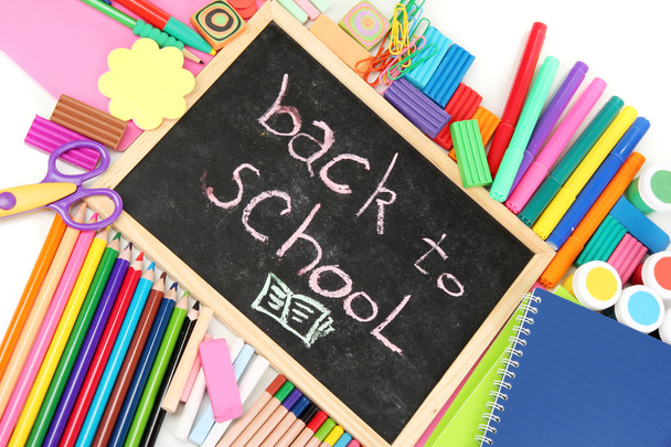 The words 'Back to School' written in chalk on the small school desk with various school supplies close-up - Foto, afbeelding