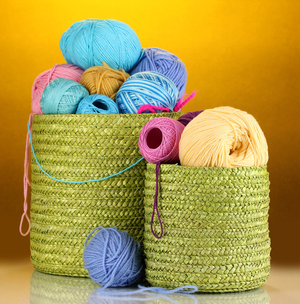 Colorful yarn for knitting in green basket on orange background - Photo, image