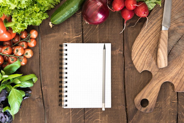 Notepad with raw vegetables on table - Photo, Image