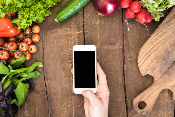 Smartphone πέρα από πίνακα με λαχανικά  - Φωτογραφία, εικόνα