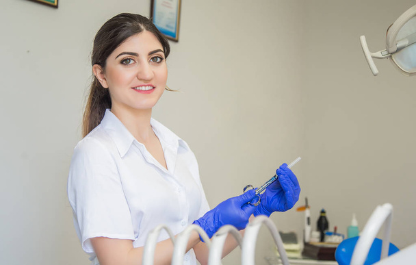 Dentista en guantes azules con jeringa de aspiración anestésica
 - Foto, Imagen